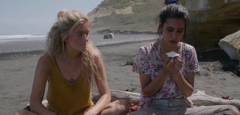 Two girls sit on the beach of a deserted island